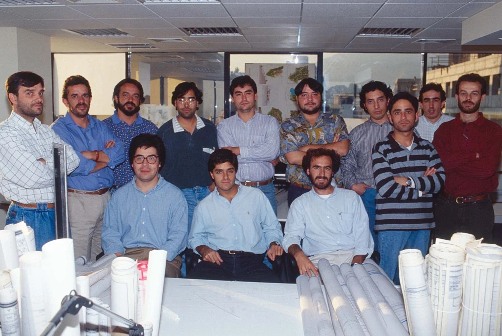 Equipo de arquitectos de ARCHIPLAN reunido en la oficina de Santiago en 2003, con planos y proyectos sobre la mesa de trabajo